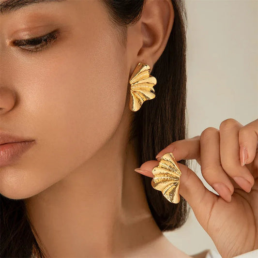 A woman's face with an earring in her ear, and the other one held between her fingers.